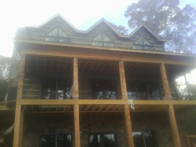 Dormers and porch framing on a large log home under construction — Roof Coating work by our crew in Clay